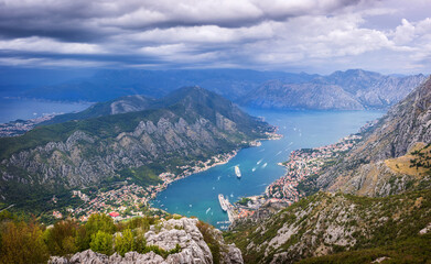 Obraz premium View of the Bay of Kotor, Montenegro, from a high mountain road with winding switchbacks. The scenic panorama includes the towns of Kotor and Tivat, and the Adriatic Sea.