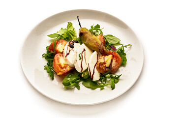 A white plate with a salad of tomatoes, cucumbers, and basil