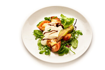 A white plate with a salad of tomatoes, cucumbers, and basil