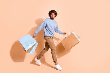 Photo of multiethnic multinational guy wear blue shirt trousers holding shopping bags walk empty...