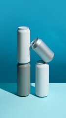 Creative composition of four aluminum beverage cans for soda, beer, energy drinks against vibrant blue background. Mockup. Simple and stylish base for product branding.