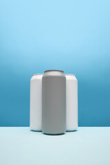 Three stylish, minimalistic grey and white cans, set against blue background. Mockup for beer, soda drinks advertisement. Simple and stylish base for product branding. Copy space for ad