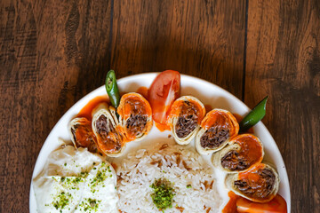 Turkish Meat Beyti Kebab with rice and yogurt served in plate isolated on wooden table closeup top view of turkish fast food
