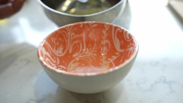 Hands of chef putting desi ghee into bowl using steel utensil in kitchen. Closeup view.