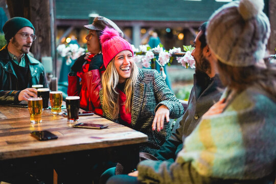 Young friends having fun together drinking craft beers at pub restaurant - Winter lifestyle and party concept - Soft focus on blond girl face