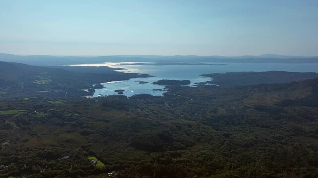 Caha Pass, County Cork, Ireland, September 2024. Drone tracks left over rolling forested hillside with the view south east to Glengarriff and the glistening North Atlantic Ocean in the distance.