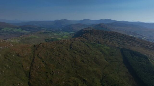 Caha Pass, County Cork, Ireland, September 2024. Drone orbits clockwise showcasing a panoramic escarpment drop off and a winding mountain road.