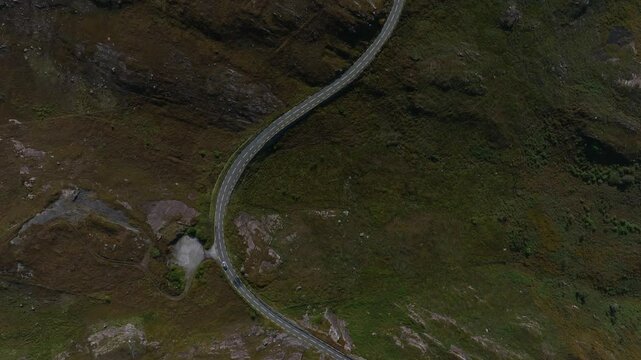 Caha Pass, County Cork, Ireland, September 2024. Drone in Bird's Eye View following a car driving along meandering mountain road near the border with County Kerry.