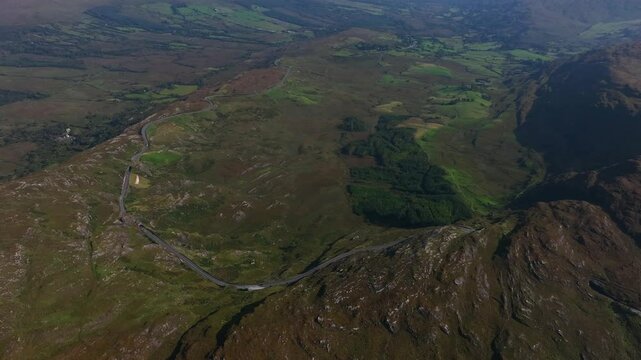 Caha Pass, County Cork, Ireland, September 2024. Drone pushes forward in a high angle panoramic overview of the winding road passing through the rugged mountain landscape on border with County Kerry.