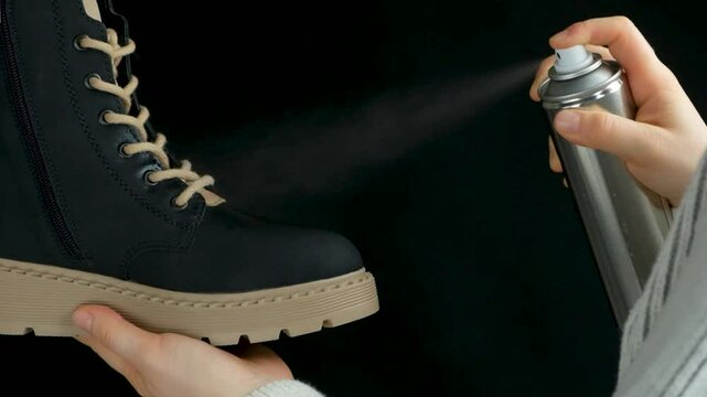 The process of applying a water-repellent protective agent from a spray can to a boot, slow motion.