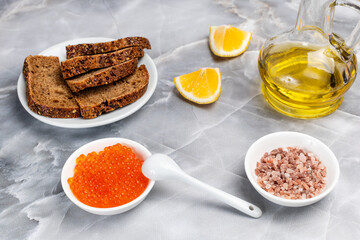 Red salmon caviar, rye bread and cooking oil on the kitchen table.