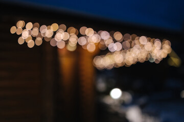 Close-up of sparkling bokeh holiday lights on a wooden cabin, capturing the cozy and festive winter atmosphere.