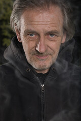 Older man uses two types of smoke machine generators on outdoor location