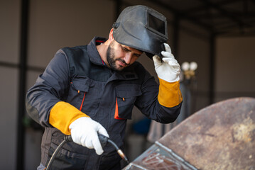 Metal worker adjusting welding helmet in workshop