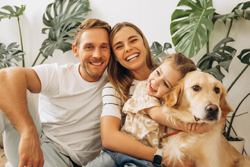 Family, happy mother, father, cute, little daughter hugging together with dog, golden retriever