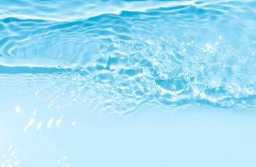 Blue water with ripples on the surface. Defocus blurred transparent blue colored clear calm water surface texture with splashes and bubbles. Water waves with shining pattern texture background.