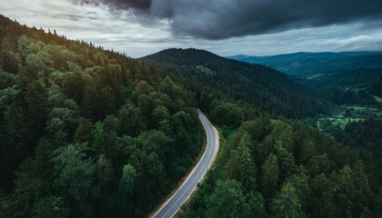 Stunning Aerial Top View of a Winding Mountain Road Surrounded by Dense Dark Green Forests, Capturing the Beauty of Natures Landscape and Offering a Serene Yet Mysterious Scenic Atmosphere