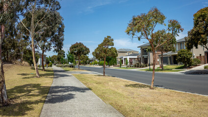 Panoramic view of a modern suburban street with eucalyptus trees and contemporary homes along the residential road. Point Cook Melbourne Australia