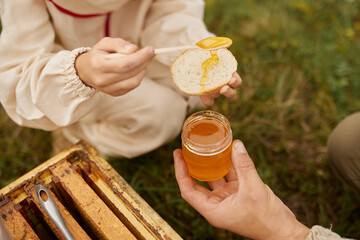 A child's hands spreading honey on a slice of bread.