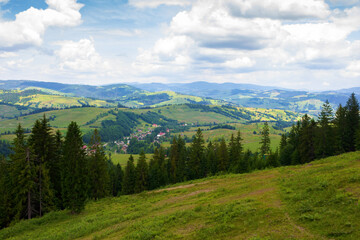 beautiful view of a countryside in carpathian mountains. rural landscape. cloudy weather in summer. trees on the steep slope. village in the valley. rolling hills in dappled light
