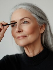 Obraz premium Senior woman applying mascara on eyelashes getting ready for the day