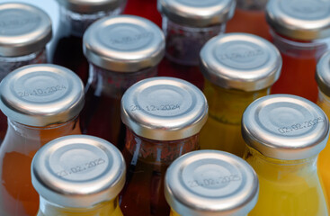 Butelki ze srebrnymi metaliwymi nakrętka na taśmie produkcyjnej z bliska 