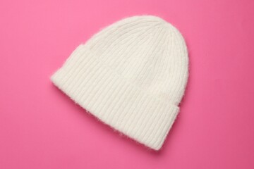 Warm woolen hat on pink background, top view