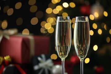 Delicious champagne in glasses against blurred lights, closeup with space for text. Christmas celebration