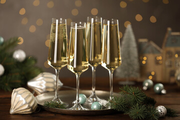 Champagne in glasses and Christmas decor on wooden table against blurred lights. Bokeh effect
