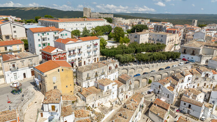 Naklejka premium Aerial view of houses and buildings in the historic center of Monte Sant'Angelo, in the province of Foggia, Apulia. It is a typical village of Southern Italy. In background is the castle of the town.