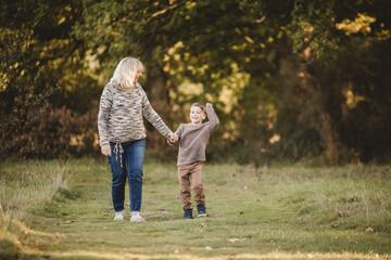 Happy Grandmother and Grandson Holding Hands Outdoors, Family Bonding in Autumn Park