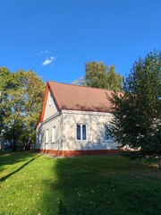 large building with a traditional design featuring red brick pillars and a gabled roof, surrounded by trees. The architecture showcases a blend of modern and classical styles, reflecting cultural