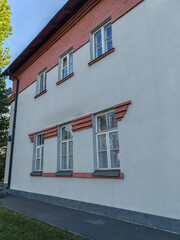large building with a traditional design featuring red brick pillars and a gabled roof, surrounded by trees. The architecture showcases a blend of modern and classical styles, reflecting cultural