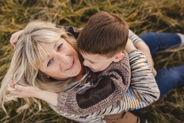 Grandmother hugging grandson outdoors autumn candid family portrait loving happy moment natural light cozy sweaters