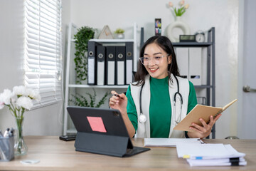 Smiling asian female doctor having video call with patient on tablet in clinic