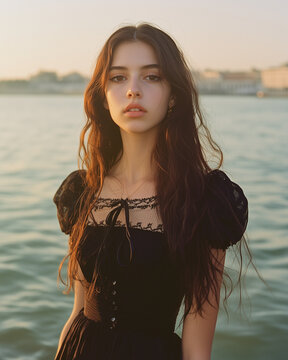 Moda - portret w stylu vogue. Młoda piękna kobieta w czarnej sukience nad wodą.