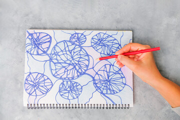 Hand holding a pencil and making neurographic drawing