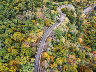 Aerial view of the Great Wall of China with autumn color leaves, a few tourists walking and a watchtower in Huairuou, near Beijing, China