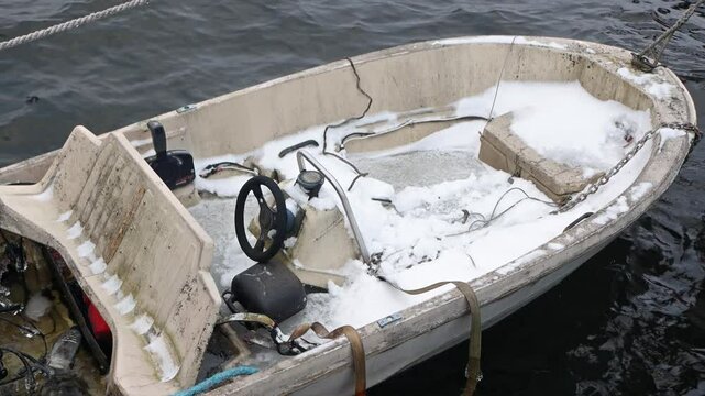 A snow-covered boat rocks on the waves