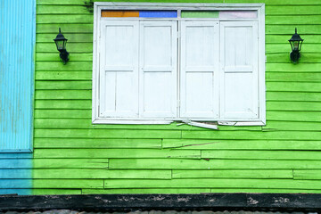 Colorful Vibrant Green Wall with a Decorative White Window Framed by Unique Lanterns in an Urban Setting