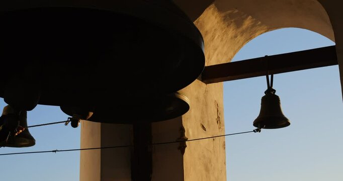 In historic Catholic church, bell ringer sounds bells, filling air with a call to prayer. Echoes create an atmosphere of reverence, uniting believers in devotion to Catholic faith.