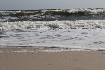Close-up of ocean waves rolling onto a sandy beach, showcasing the dynamic beauty of nature and...