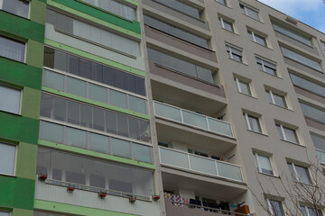 A contemporary modern apartment building featuring sleek glass balconies set against a vibrant blue sky