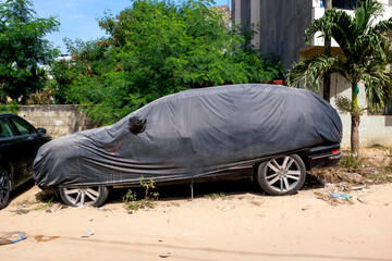 une voiture sous une bâche de protection dans une rue de Dakar au Sénégal en Afrique de l'Ouest