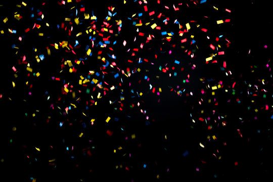 Colorful and multiform glitter confetti explosion on a black background, studio shot. Moment of happiness and festivity concept.