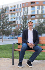 Fototapeta premium Man sitting on a bench in the park calm and smiling