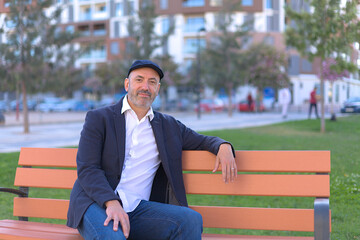 Fototapeta premium Man sitting on a bench in the park calm and smiling