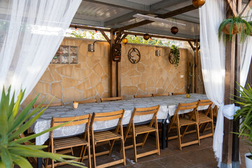 Inviting ambiance of a covered patio with a long wooden table, chairs, white curtains, and hanging...