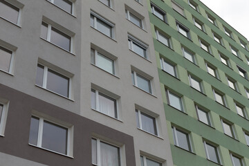A striking exterior view showcasing a multistory apartment building set against gray and green backgrounds
