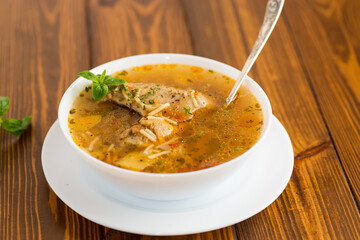 hot cooked chicken and noodle soup in a plate on a wooden table